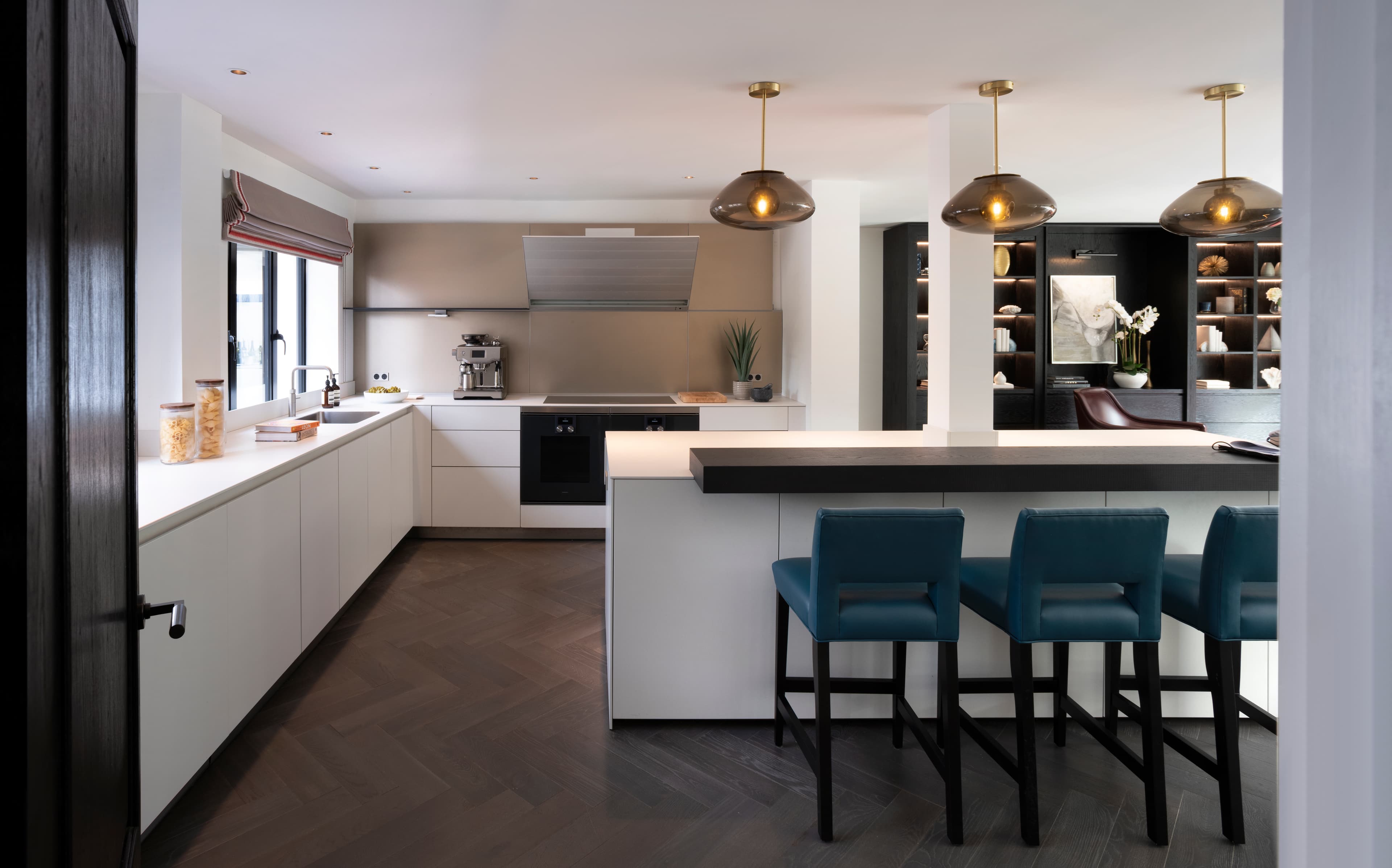 Contemporary open-plan kitchen with dark shelving and blue stools
