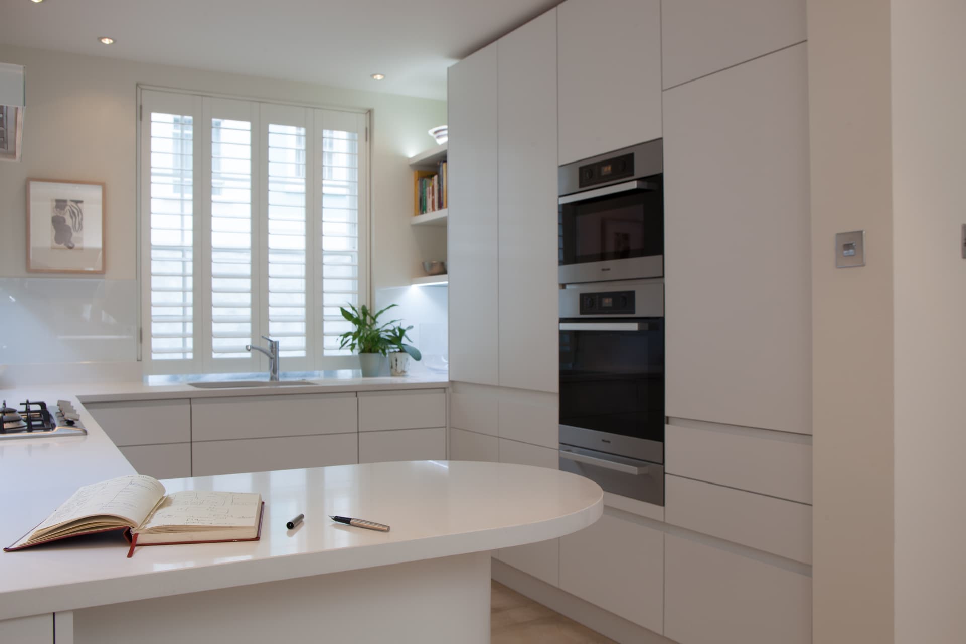 Modern fitted kitchen with integrated ovens and plantation shutters