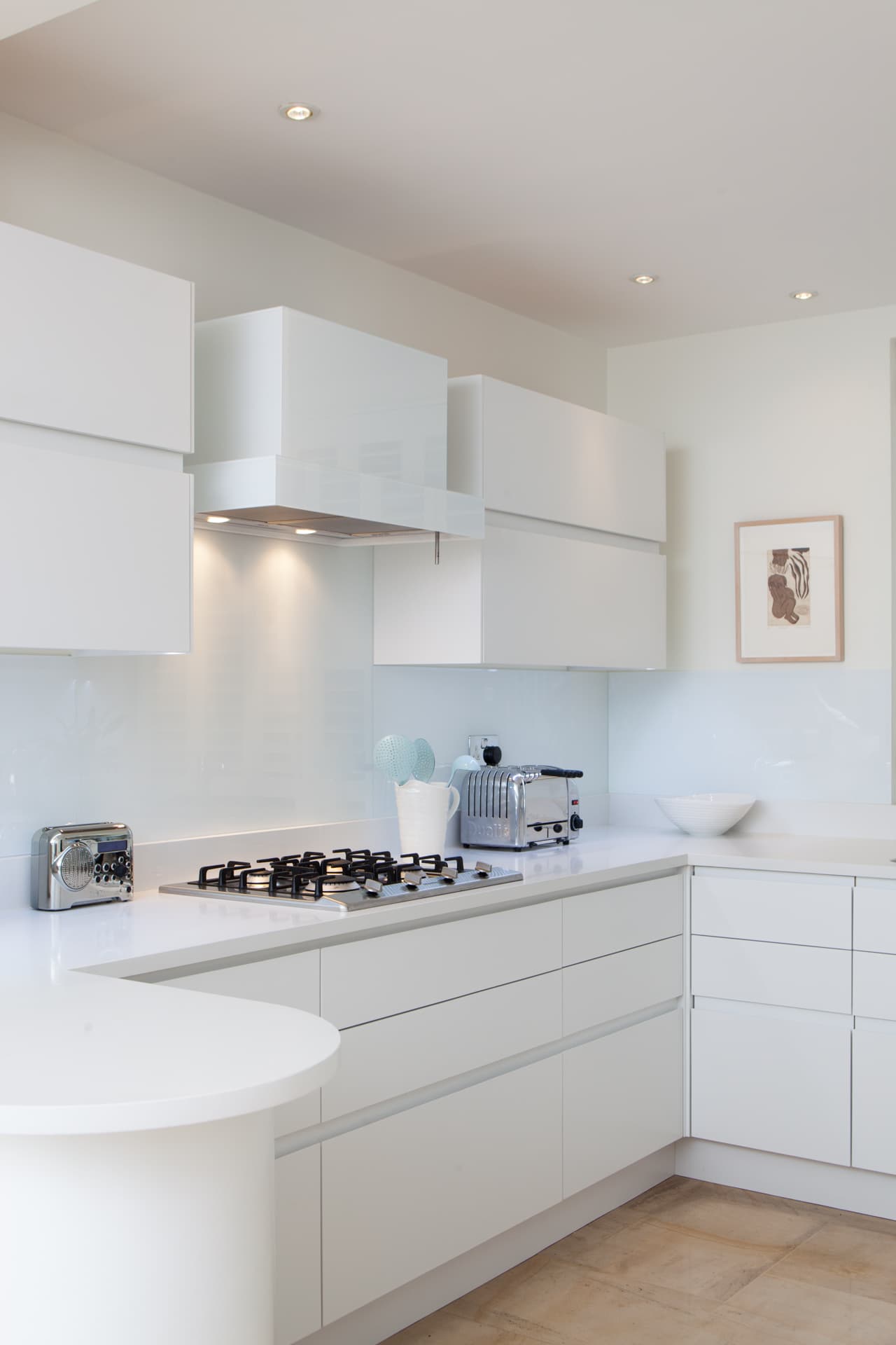 Modern white kitchen with glass splashback and curved island