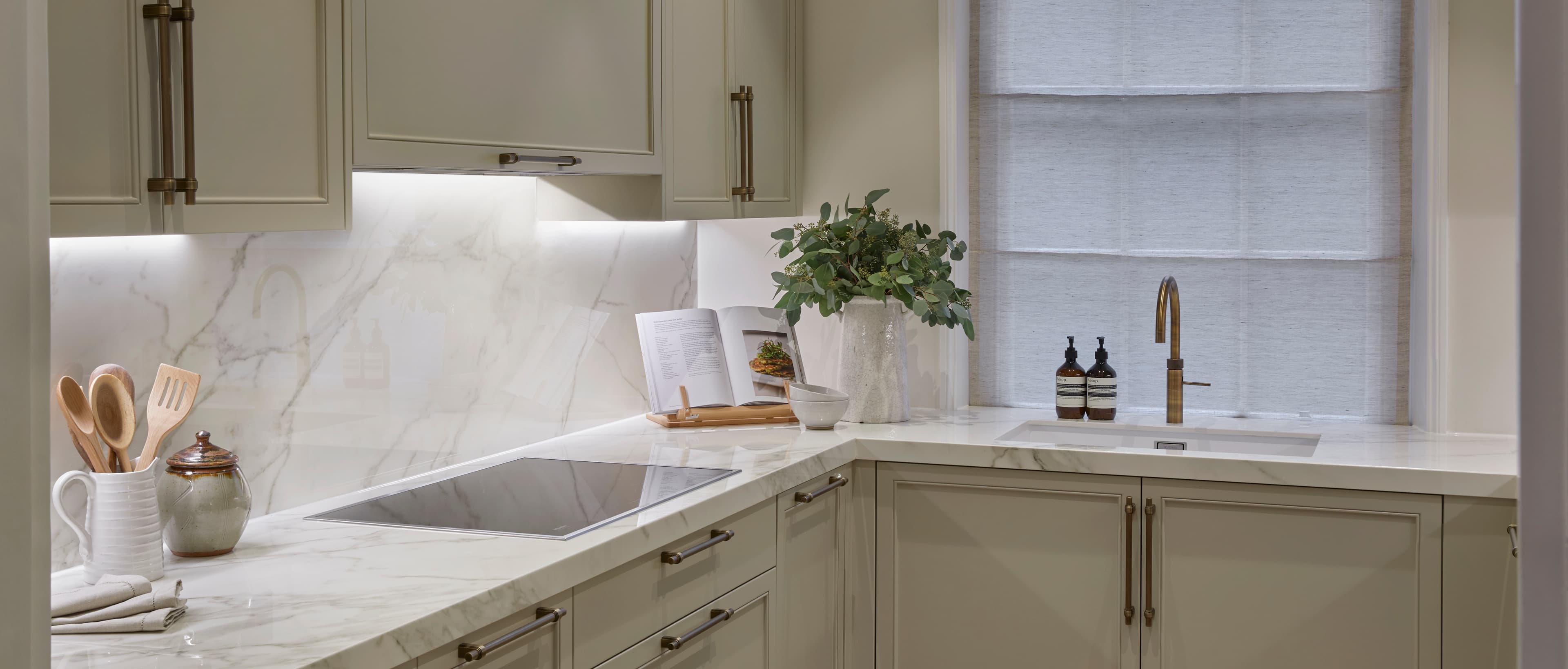Sage green utility space with marble and brass fixtures
